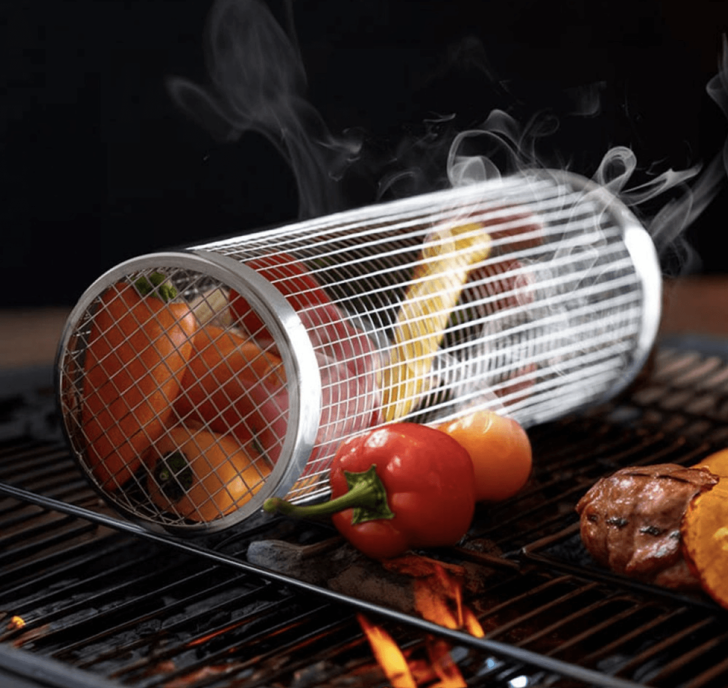 Stainless steel rolling grill basket with colorful vegetables on a BBQ